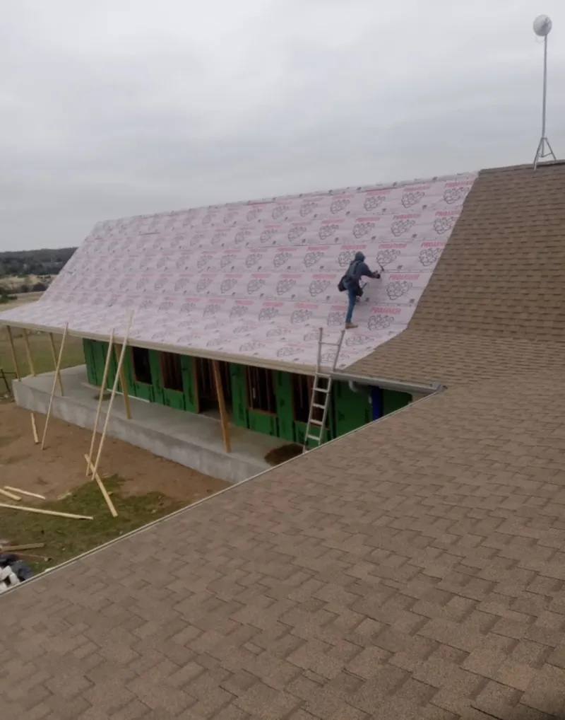 Worker preparing underlayment for a metal roof installation in Forest Park